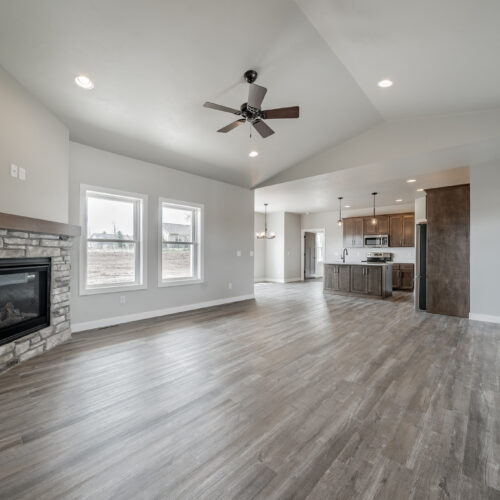 Wide-angle image showing a living room with the kitchen in the background, highlighting the open-plan design, modern furnishings in the living area, and the kitchen's sleek appearance, creating a cohesive and inviting space.