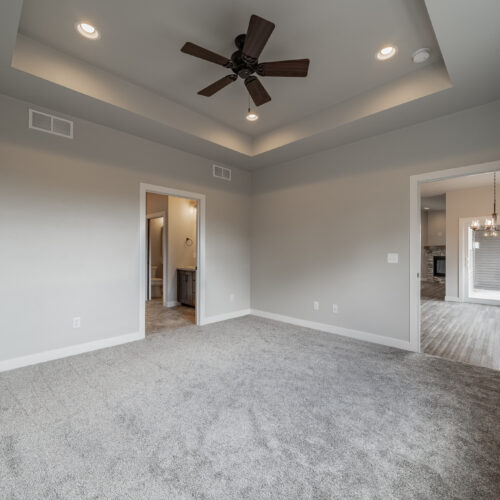 Side-angle view of a new home's master bedroom, showing modern design and spaciousness.