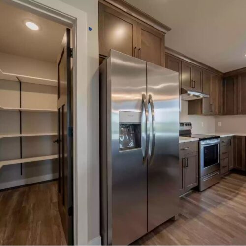 Close-up photo of the stainless steel refrigerator and kitchen pantry in the Milestone floor plan. The image highlights the sleek, modern design of the refrigerator and the spacious, well-organized layout of the pantry, reflecting a balance of style and practicality in the kitchen.